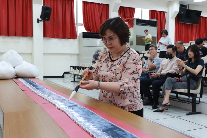 中華醫大校長李碧娥博士手持考試院贈送的硃砂筆為考生應試用的2B鉛筆進行硃砂點筆儀式。