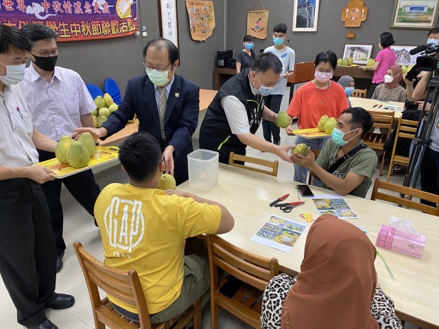 華醫大孫逸民校長(左三)偕同臺南市驗光生公會理事長吳浩銘(左四)分送文旦柚給外籍生