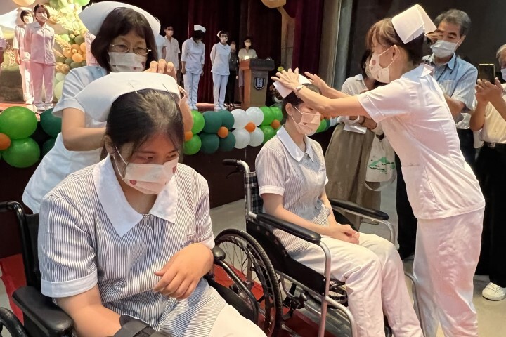 車禍受傷的朱怡蓁和楊心淳同學乘坐輪椅在台下接受系主任蔡富棉和老師加冠