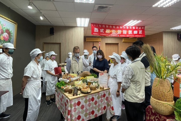 臺南市政府勞工局局長王鑫基(中左)參觀學員製作的各式麵包、西點等成果