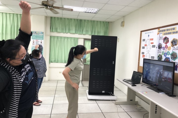 中華醫大USR南關線智慧健康幸福團隊成員在智慧健康資訊整合實訓中心透過視訊指導長者做居家運動