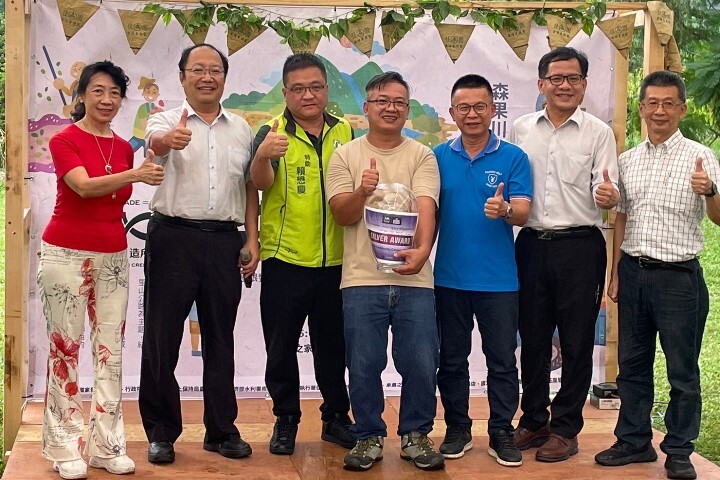 中華醫大USR團隊召集人孫逸民校長(左二)、王靖婷老師(左一)將國際宜居社區銀獎獻給楠西密枝里社區發展協會理事長江仲緯(中)