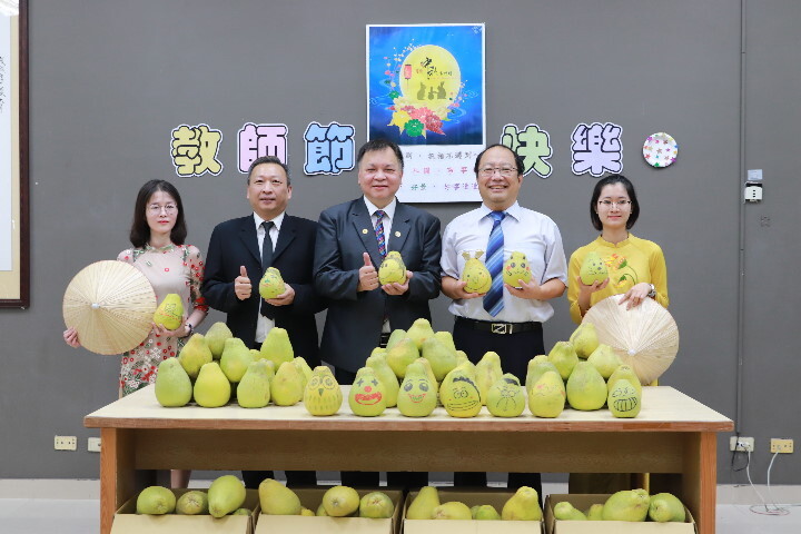 臺南市驗光生公會理事長吳浩銘(中)、副理事長王智平(左二)代表公會致贈文旦柚向老師致敬,也讓外籍生體驗台灣人過中秋吃文旦的特色,由孫逸民校長(右二)帶外籍生代表接受